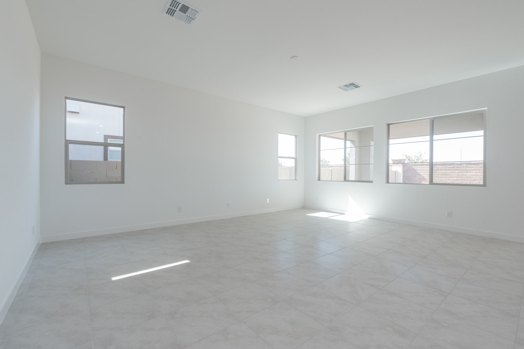 A bright, spacious room with large windows, a concrete floor, and minimal furnishings, creating a clean and minimalist atmosphere.