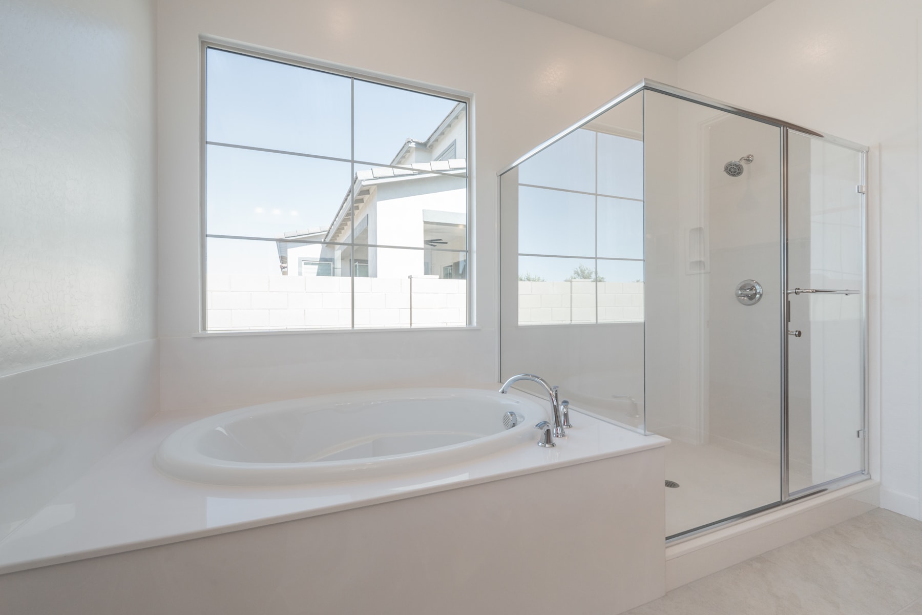 A spacious and modern bathroom with a large bathtub, a glass-enclosed shower, and large windows providing ample natural light.