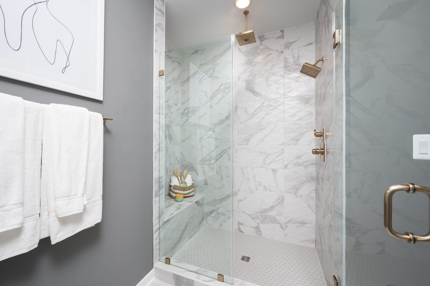 A modern, minimalist bathroom with a large, marble-tiled shower enclosure and a white towel hanging on the wall.
