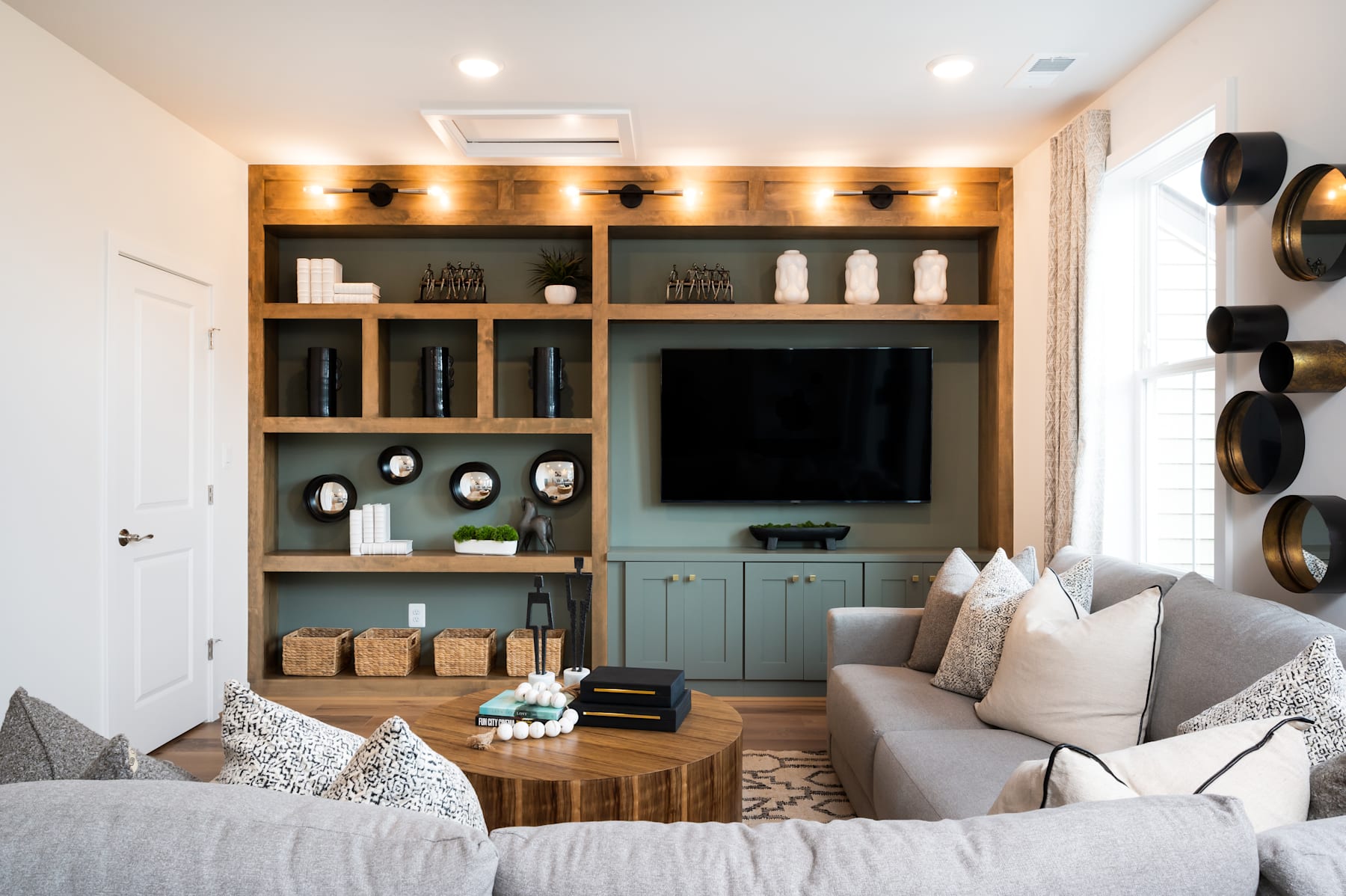 A cozy and well-designed living room with a large built-in shelving unit, a comfortable sofa, and various decorative elements such as pillows, artwork, and lighting fixtures.