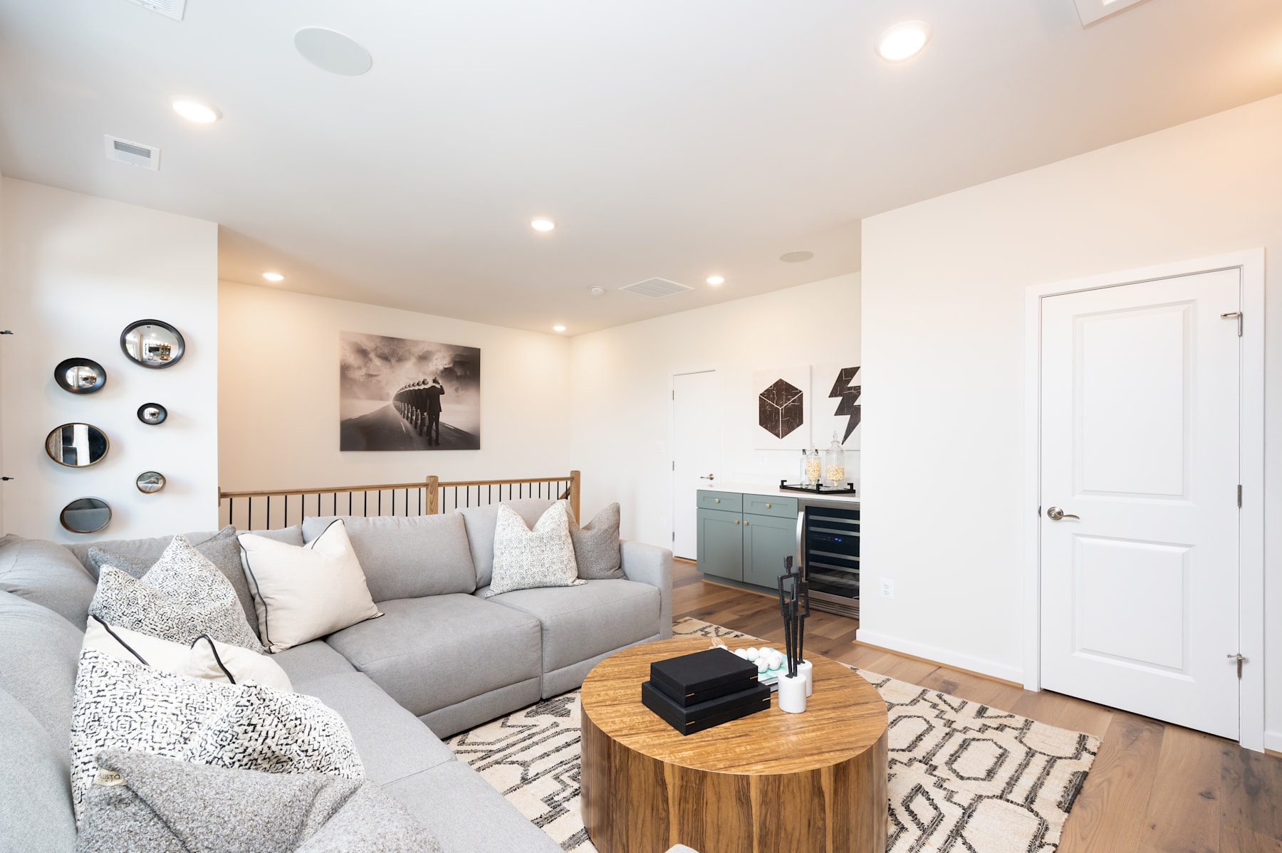 A cozy living room with a gray sofa, decorative wall art, and a wooden side table in the foreground, set against a bright and airy background.
