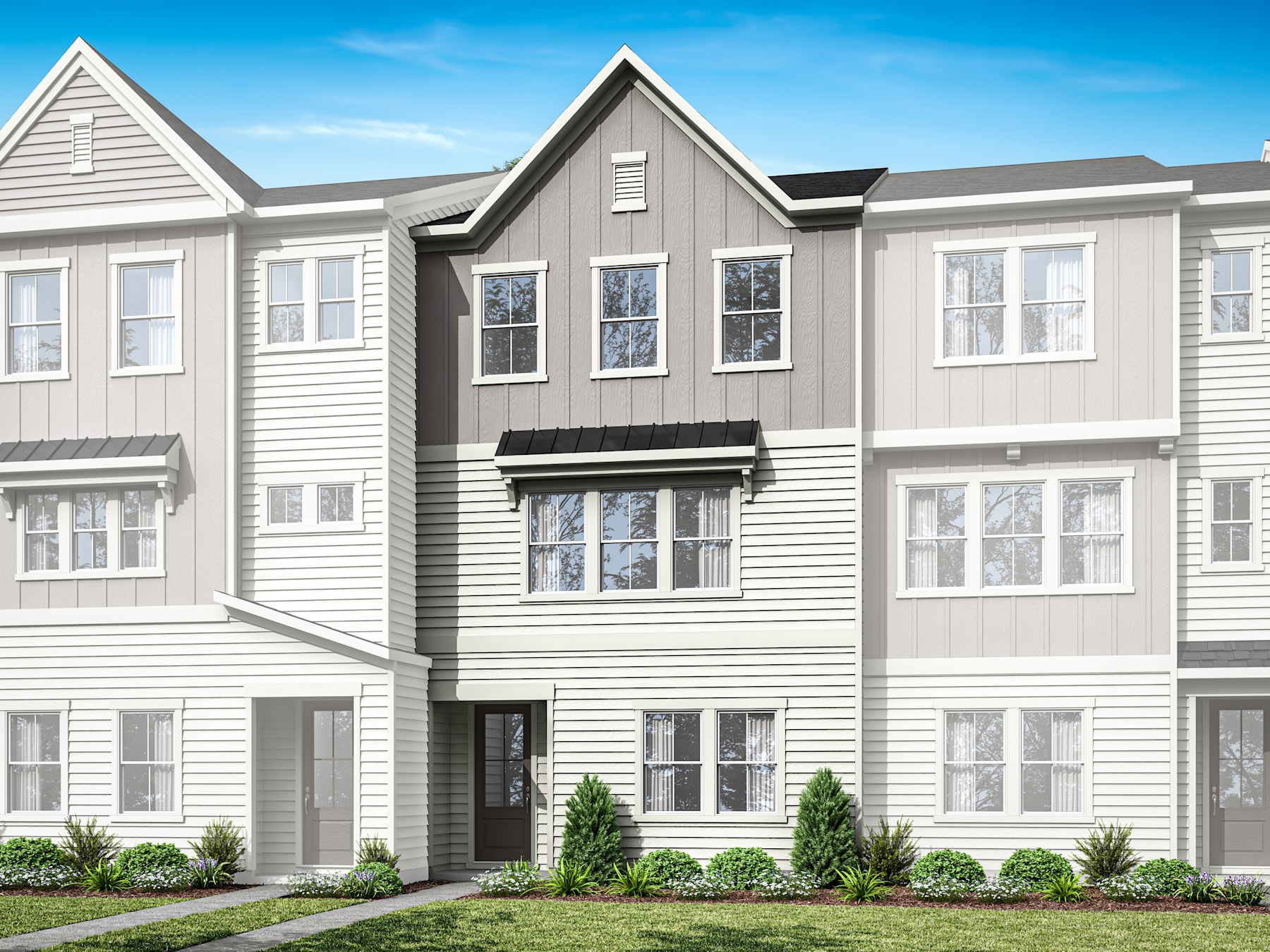 A multi-story townhouse with a gray exterior, white trim, and a landscaped front yard against a clear blue sky.