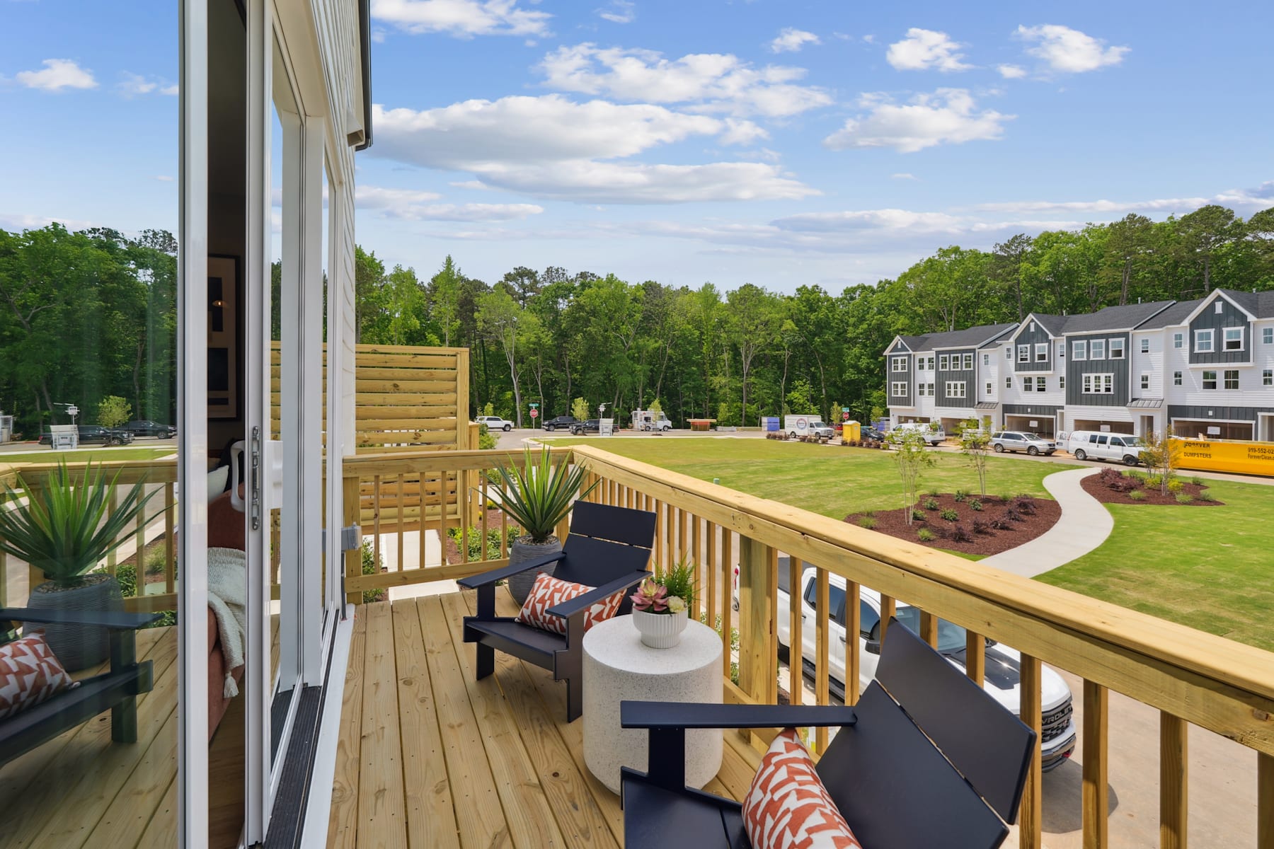 A wooden deck overlooking a grassy area with trees and buildings in the background, creating a peaceful and scenic outdoor setting.
