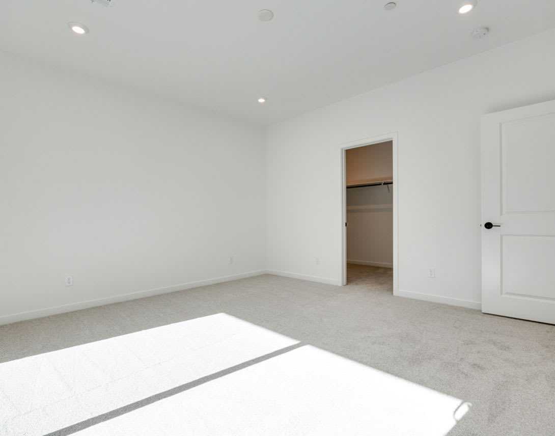 A bright, minimalist room with a closet and a window letting in natural light, creating a clean and airy atmosphere.
