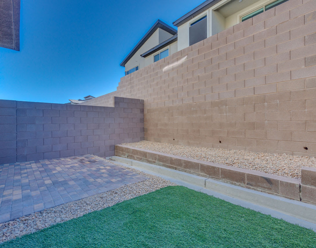 A paved walkway leads to a building with a brick exterior, surrounded by a grassy area and a clear blue sky.