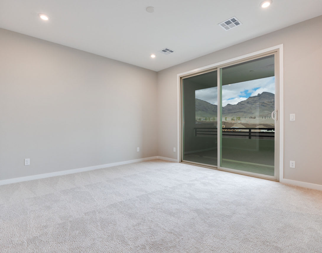 A spacious, well-lit room with a sliding glass door leading to a scenic outdoor view of mountains in the background.