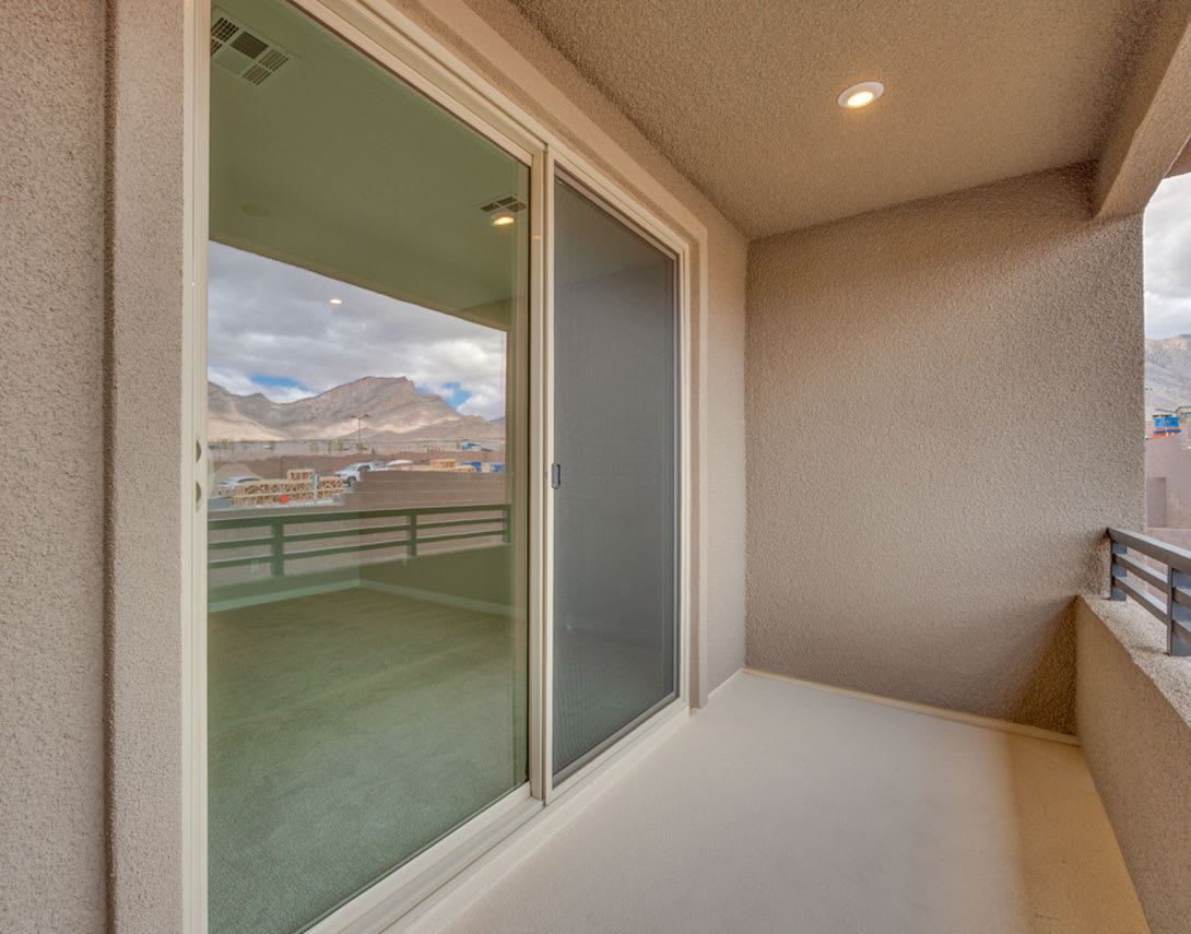 The image shows a balcony or patio with sliding glass doors that offer a scenic view of mountains in the background.