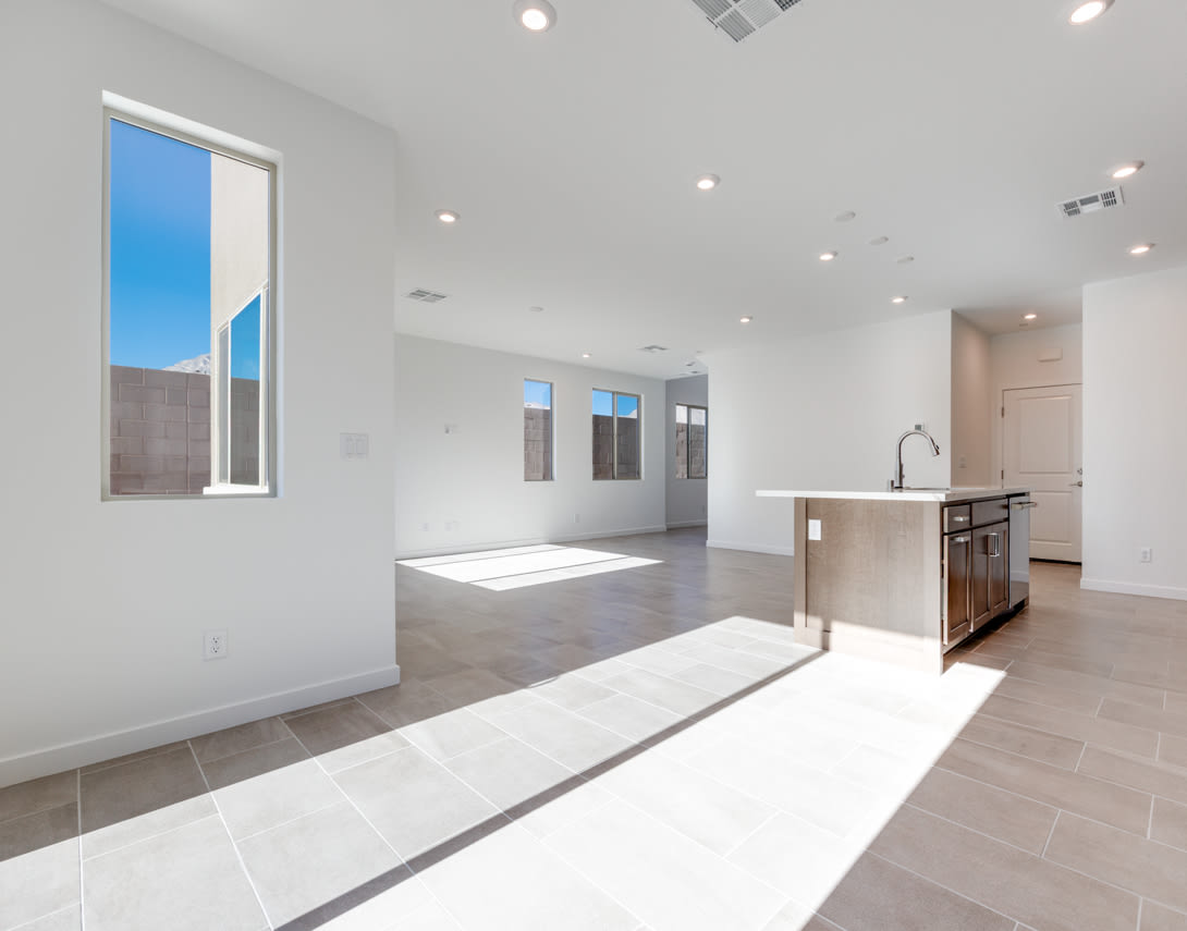 A spacious, modern interior with a bright, open layout featuring a kitchen area, hardwood floors, and large windows allowing natural light to flood the space.