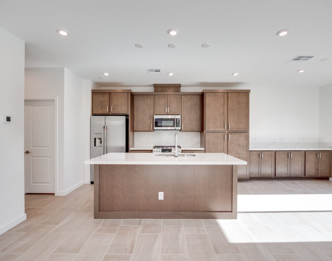 A modern, open-concept kitchen with light wood cabinets, a central island, and stainless steel appliances, set against a bright and airy background.