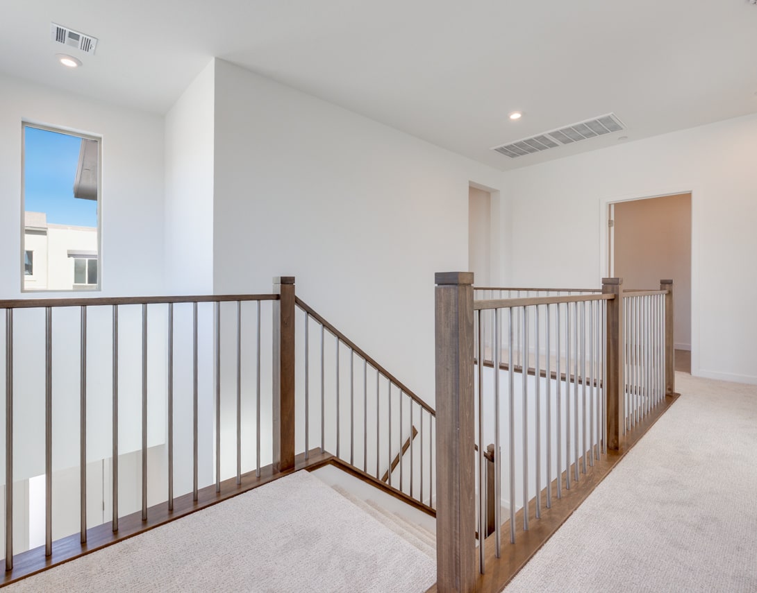 A bright and spacious hallway with a wooden railing leading to multiple rooms, creating an inviting and open atmosphere.