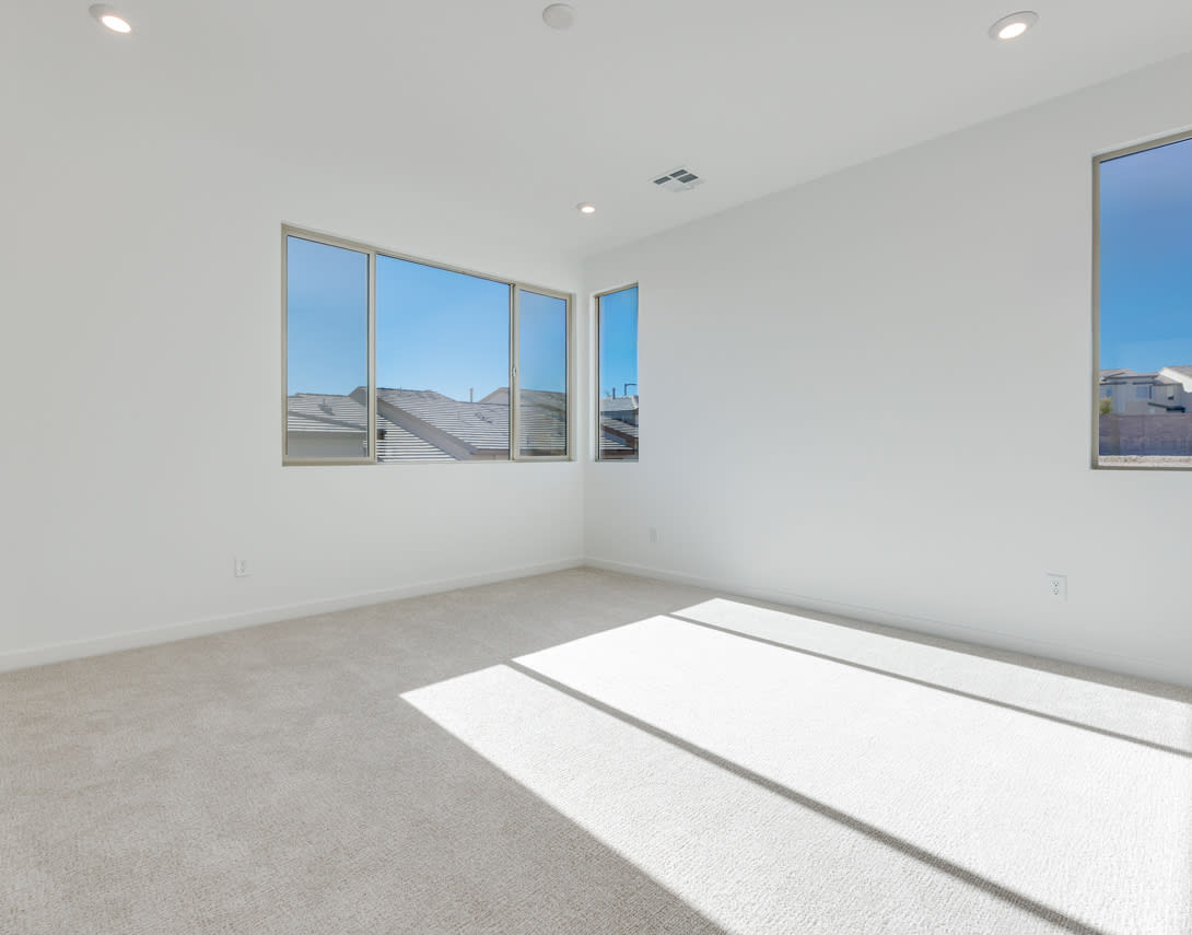 A bright and spacious room with large windows overlooking the exterior, featuring a clean and minimalist design with a smooth concrete floor.