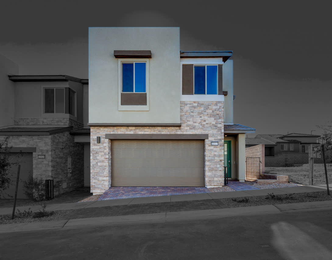 A modern two-story residential building with a stone facade, a garage door, and large windows that reflect the surrounding environment.