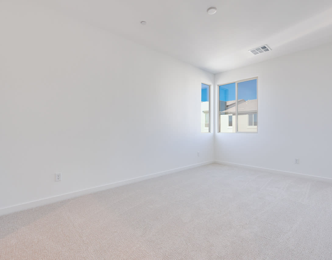 A bright, empty room with a large window overlooking a residential area in the background.