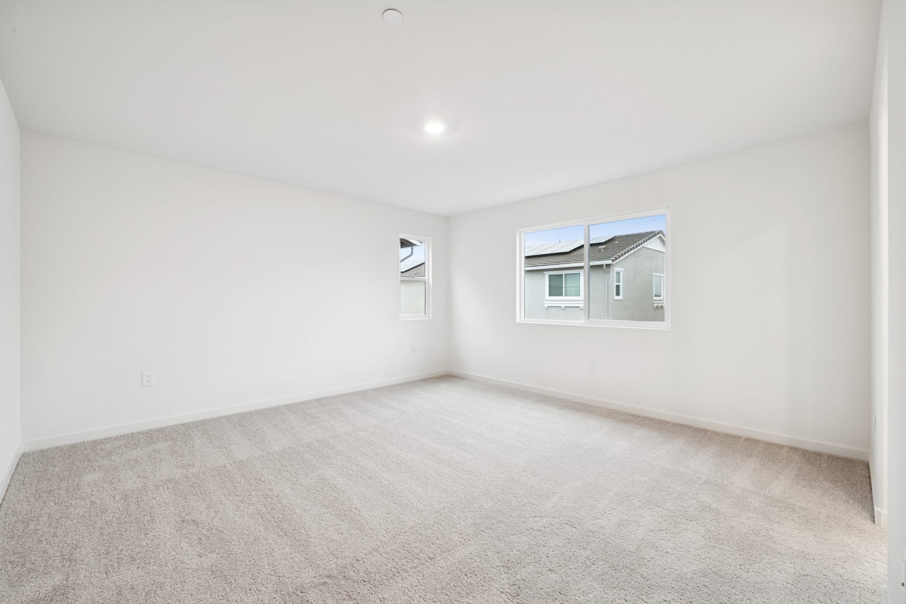 A simple, minimalist room with a window overlooking a residential area in the background.