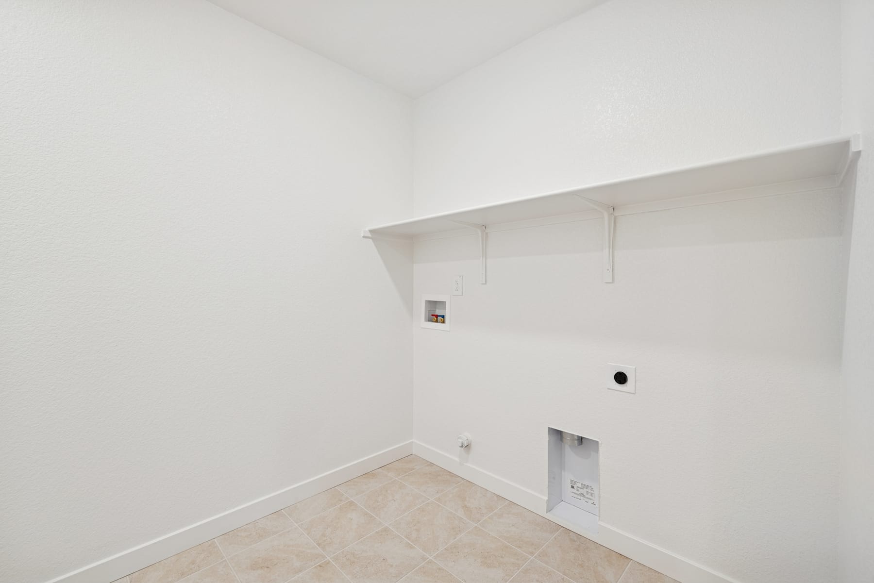 A simple, minimalist room with white walls, a light-colored floor, and a recessed area with hooks for hanging items.