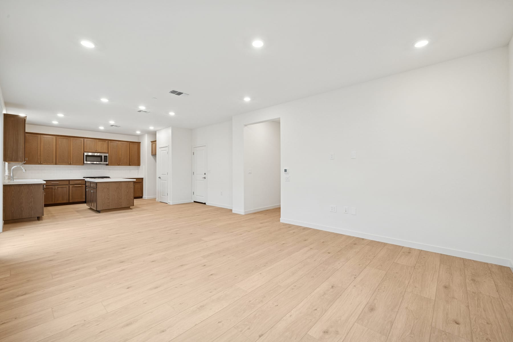 A spacious, open-concept living area with a modern kitchen, hardwood floors, and recessed lighting, creating a bright and airy atmosphere.