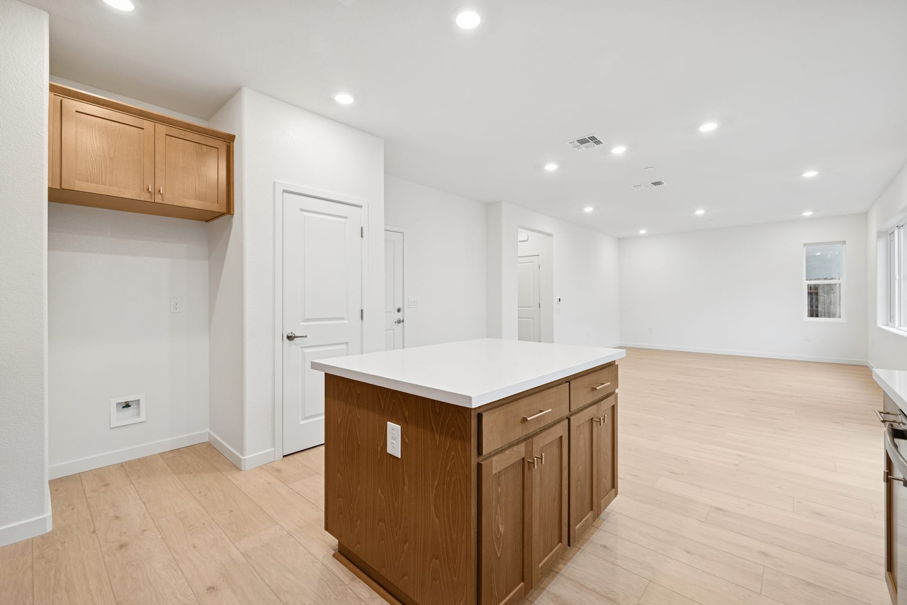 A spacious and well-lit room with a wooden kitchen island, white walls, and hardwood floors.