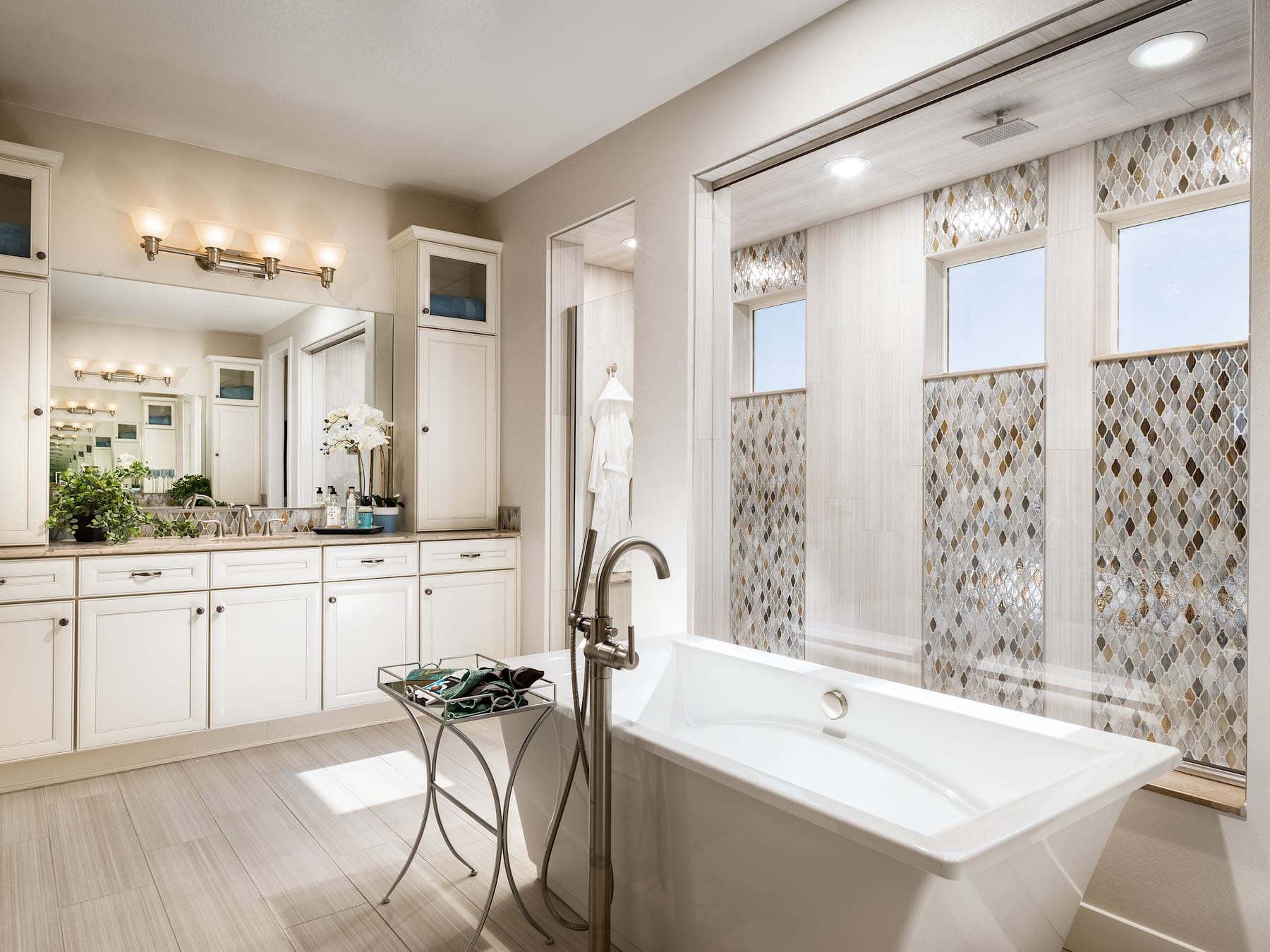 A spacious and well-designed bathroom with a freestanding bathtub, vanity with double sinks, and decorative tile accents on the walls.