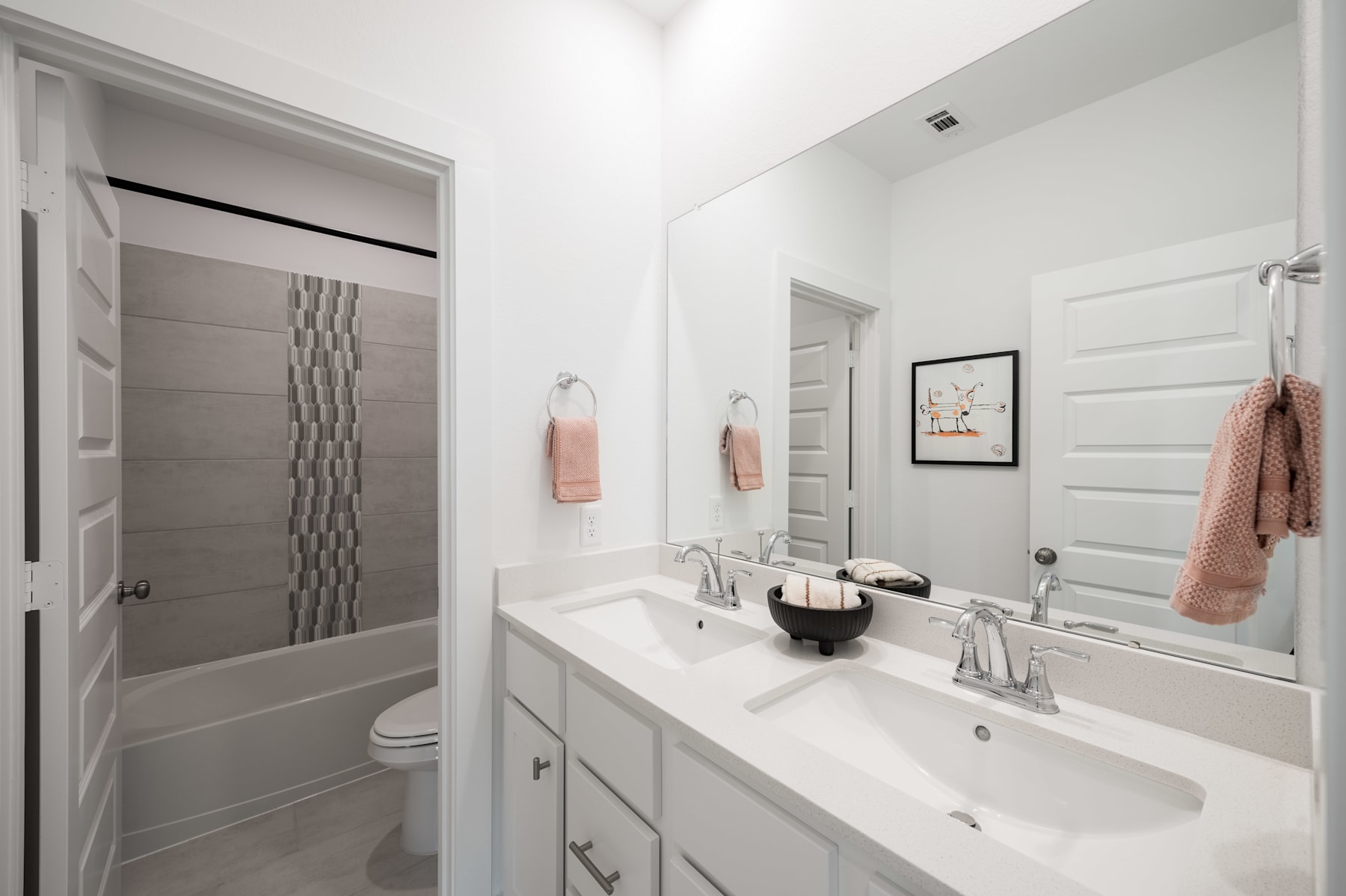 A modern, well-lit bathroom with a vanity, sink, and mirror, along with a shower curtain and towels in a neutral color scheme.