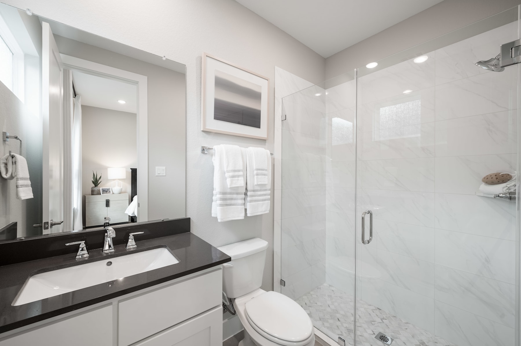 A modern, well-lit bathroom with a vanity, mirror, and a glass-enclosed shower area, all in a clean, minimalist design.