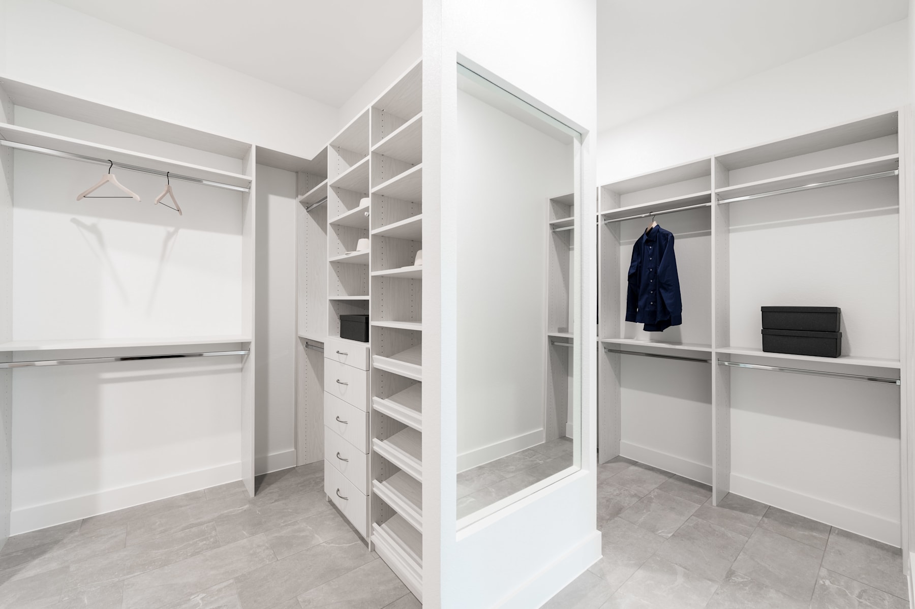 A spacious and well-organized walk-in closet with ample shelving, hanging rods, and drawers, providing an efficient storage solution in a minimalist and clean-looking environment.