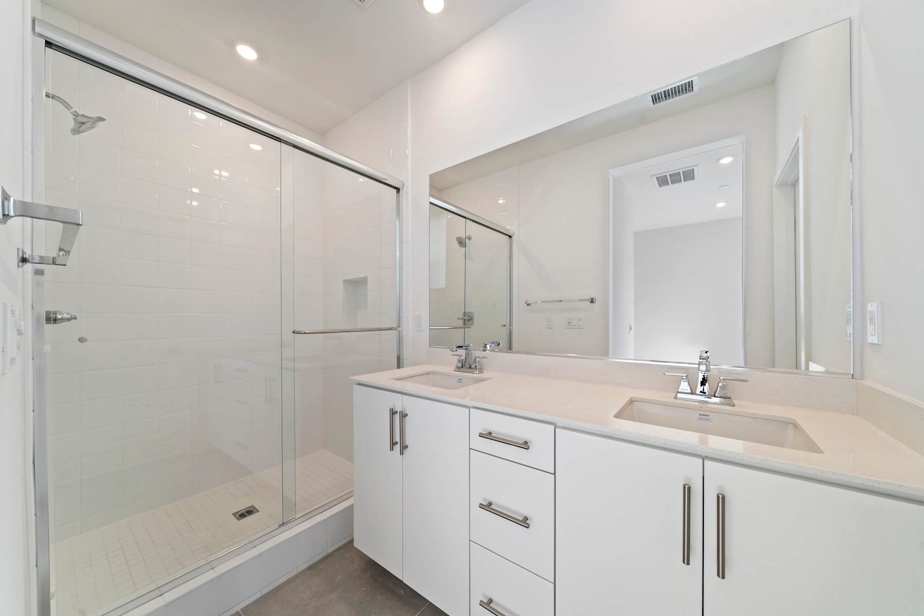 A modern, well-lit bathroom with a white vanity, a large mirror, and a glass-enclosed shower area.