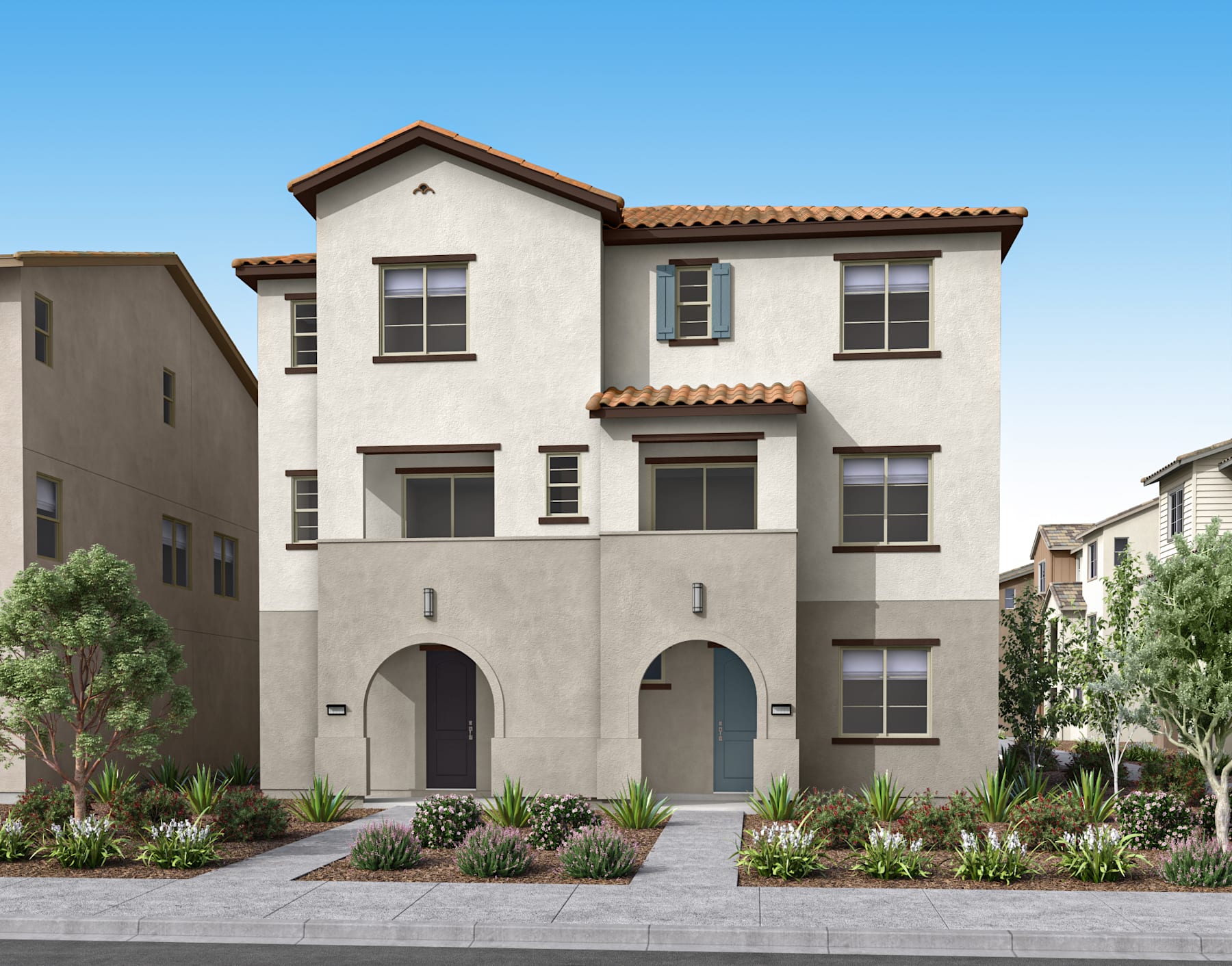 A multi-story Mediterranean-style residential building with a tiled roof, arched entryways, and lush landscaping in the foreground, set against a clear blue sky.