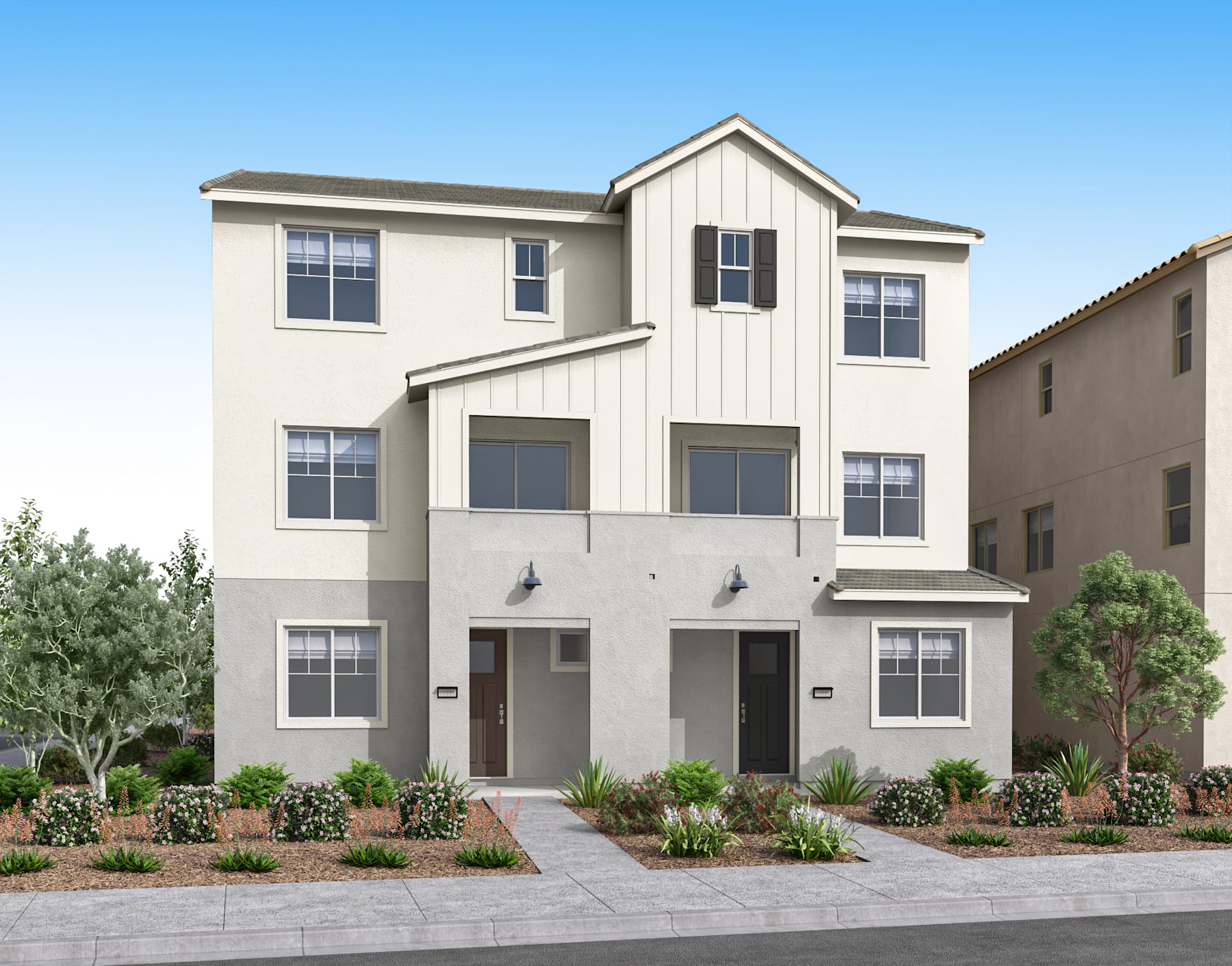 A two-story residential building with a white exterior, surrounded by landscaped gardens and a clear blue sky in the background.