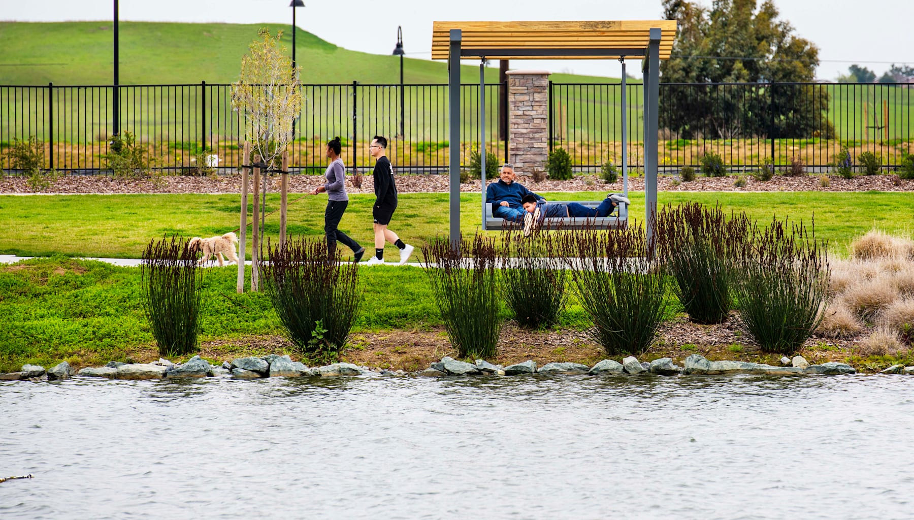 A well-designed outdoor public space with a grassy area, a bench, and people enjoying the surroundings.