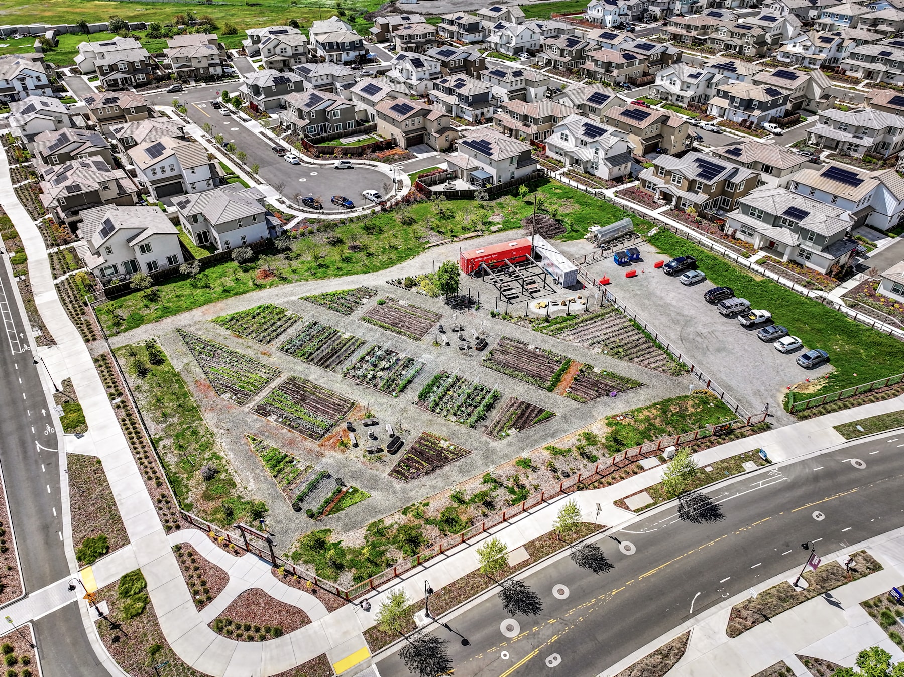 A densely populated residential area with various buildings, roads, and a large community garden or agricultural plot in the foreground.