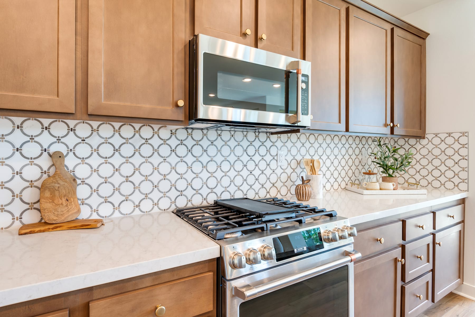 A modern kitchen with wooden cabinets, a gas stove, and a patterned tile backsplash.