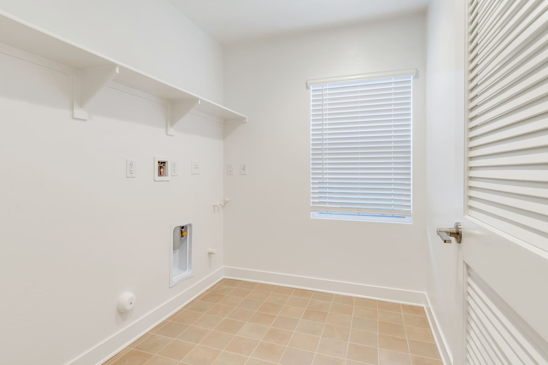 A bright, minimalist room with white walls, a tiled floor, and a window with horizontal blinds.