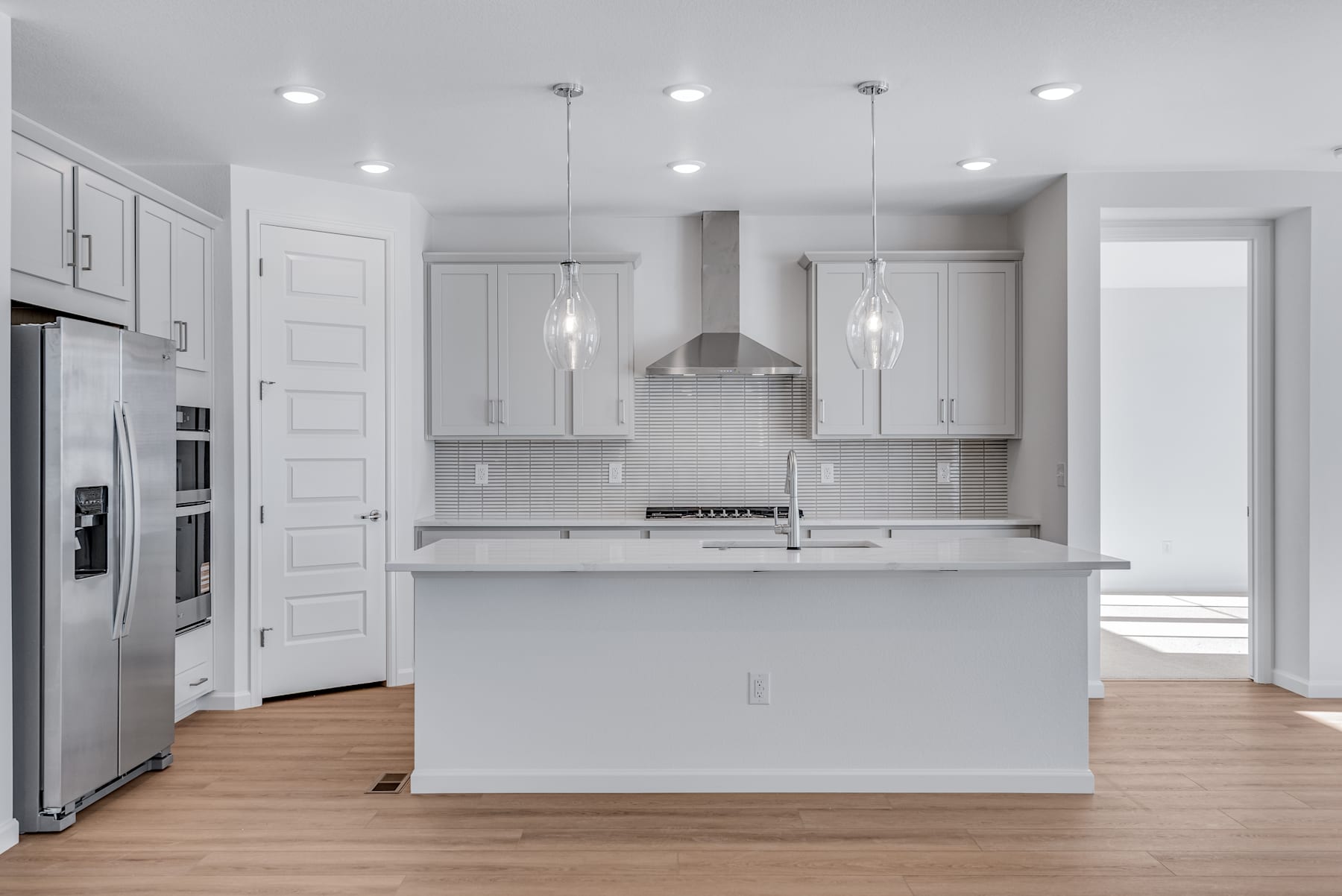 A modern, bright, and spacious kitchen with white cabinets, stainless steel appliances, and a central island with a countertop.