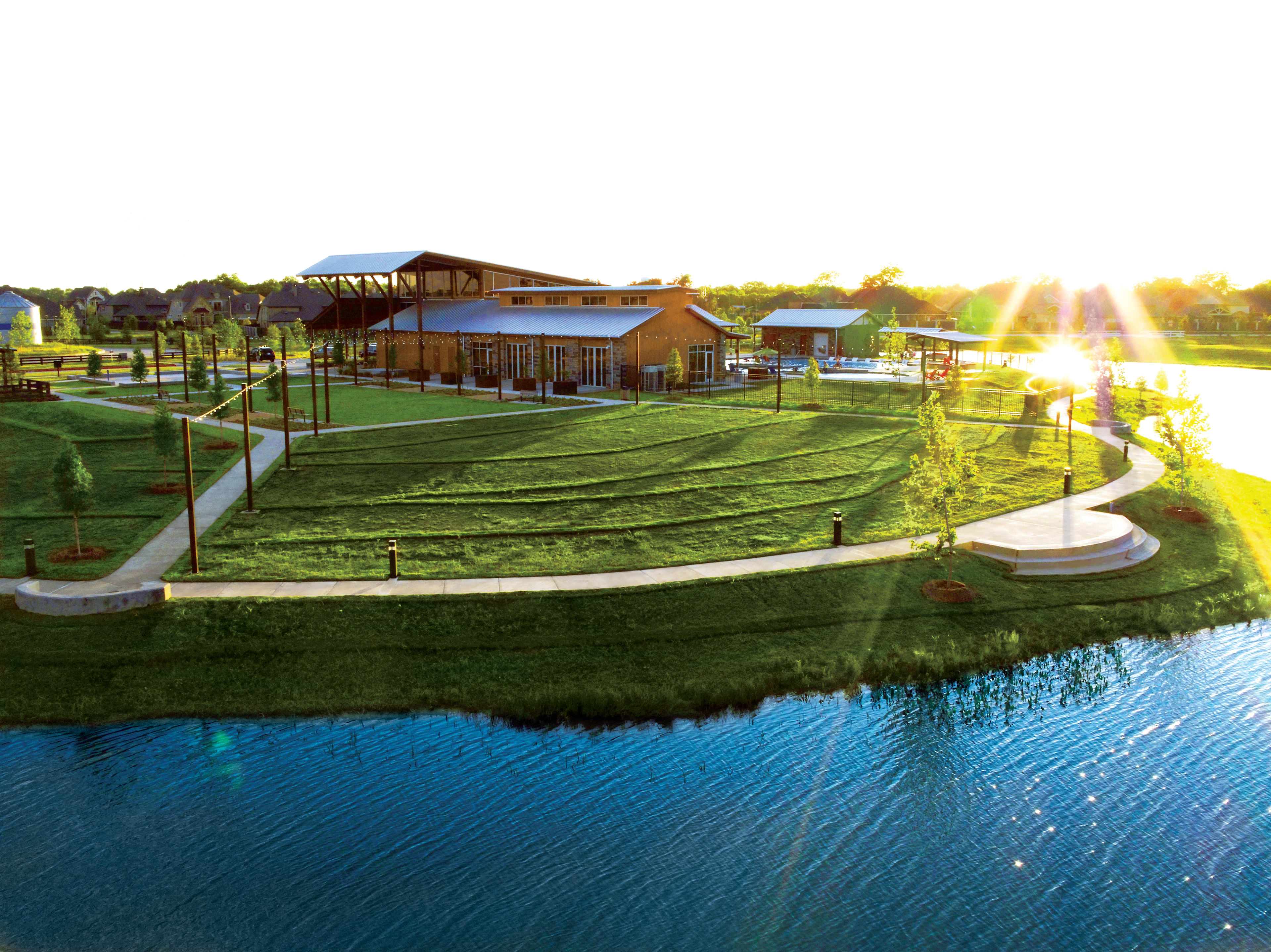 A scenic outdoor area with a large body of water, lush green grass, and a wooden structure with a covered patio overlooking the landscape.