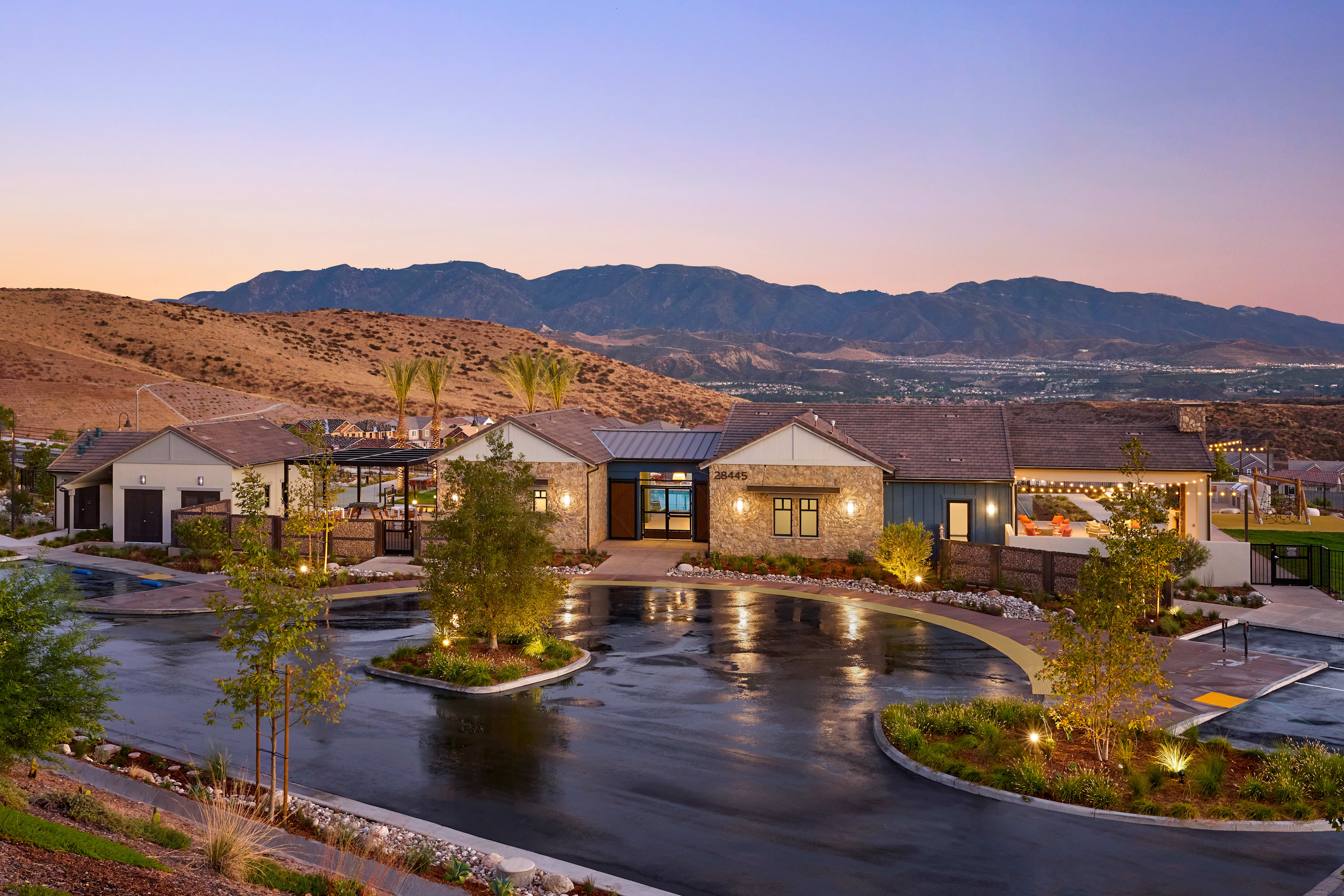 A tranquil outdoor setting with a pond surrounded by lush greenery, against the backdrop of a mountainous landscape bathed in the warm glow of sunset.
