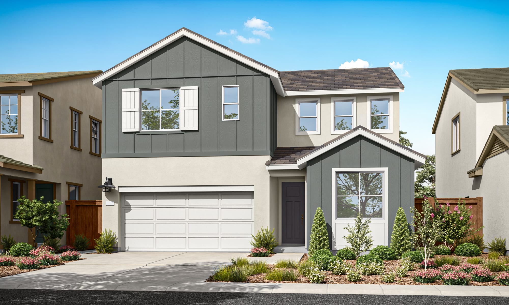 A two-story residential house with a gray exterior, a white garage door, and a well-landscaped front yard featuring various plants and flowers.