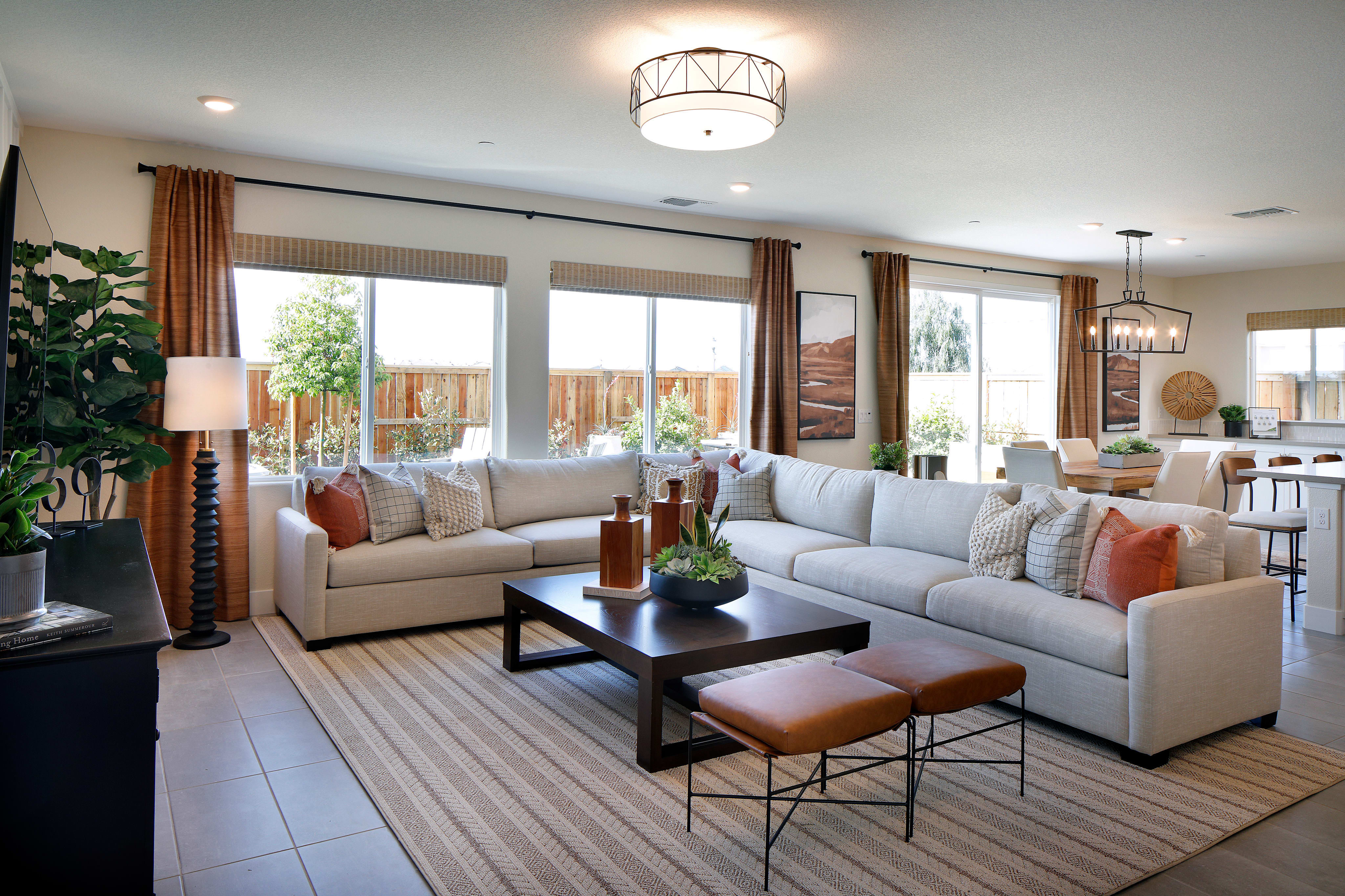 A cozy and inviting living room with a comfortable L-shaped sofa, a coffee table, and a large window overlooking a backyard with lush greenery.
