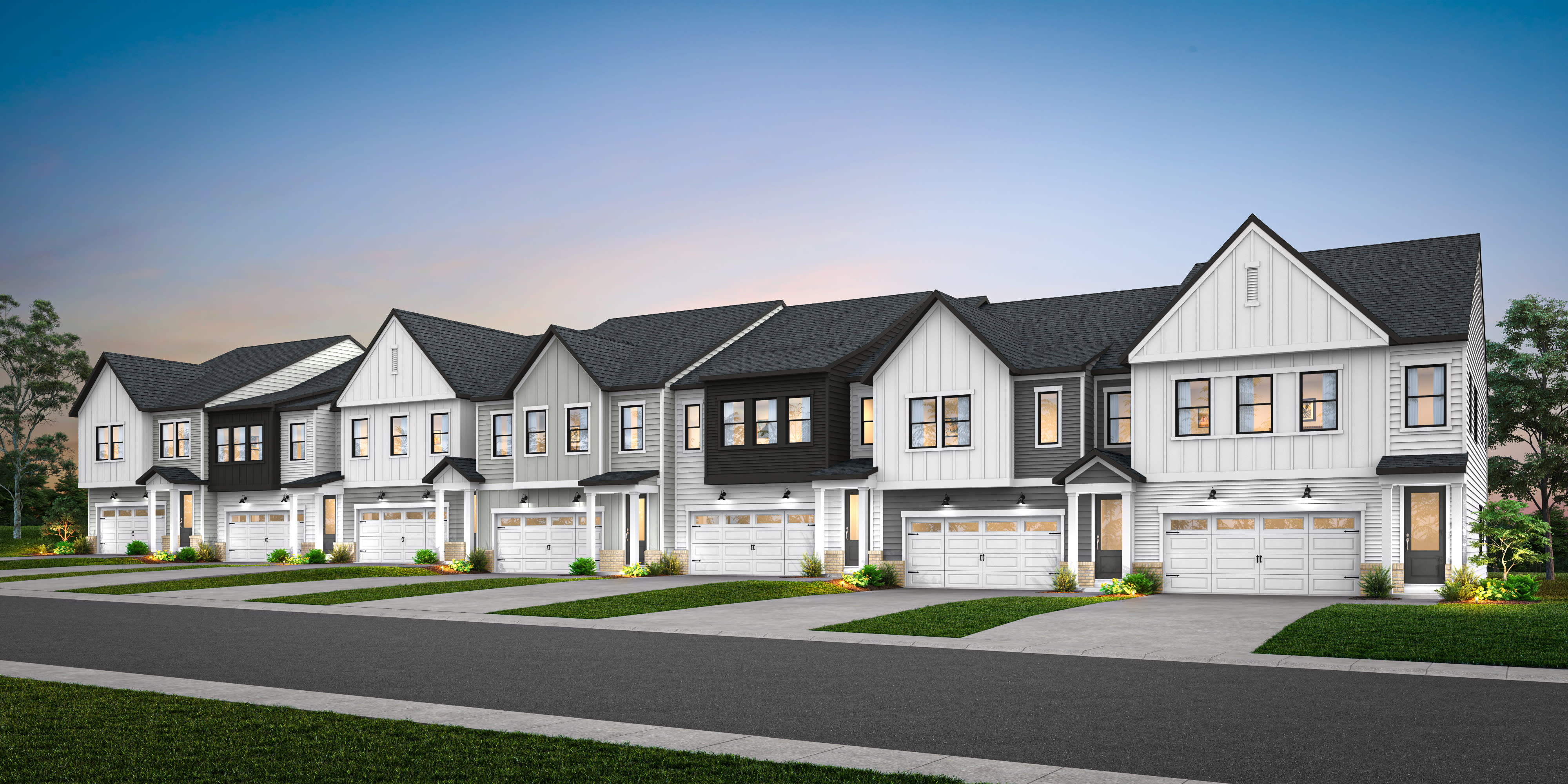 A row of modern, two-story townhouses with white siding, black roofs, and attached garages, set against a clear blue sky and surrounded by lush green grass.