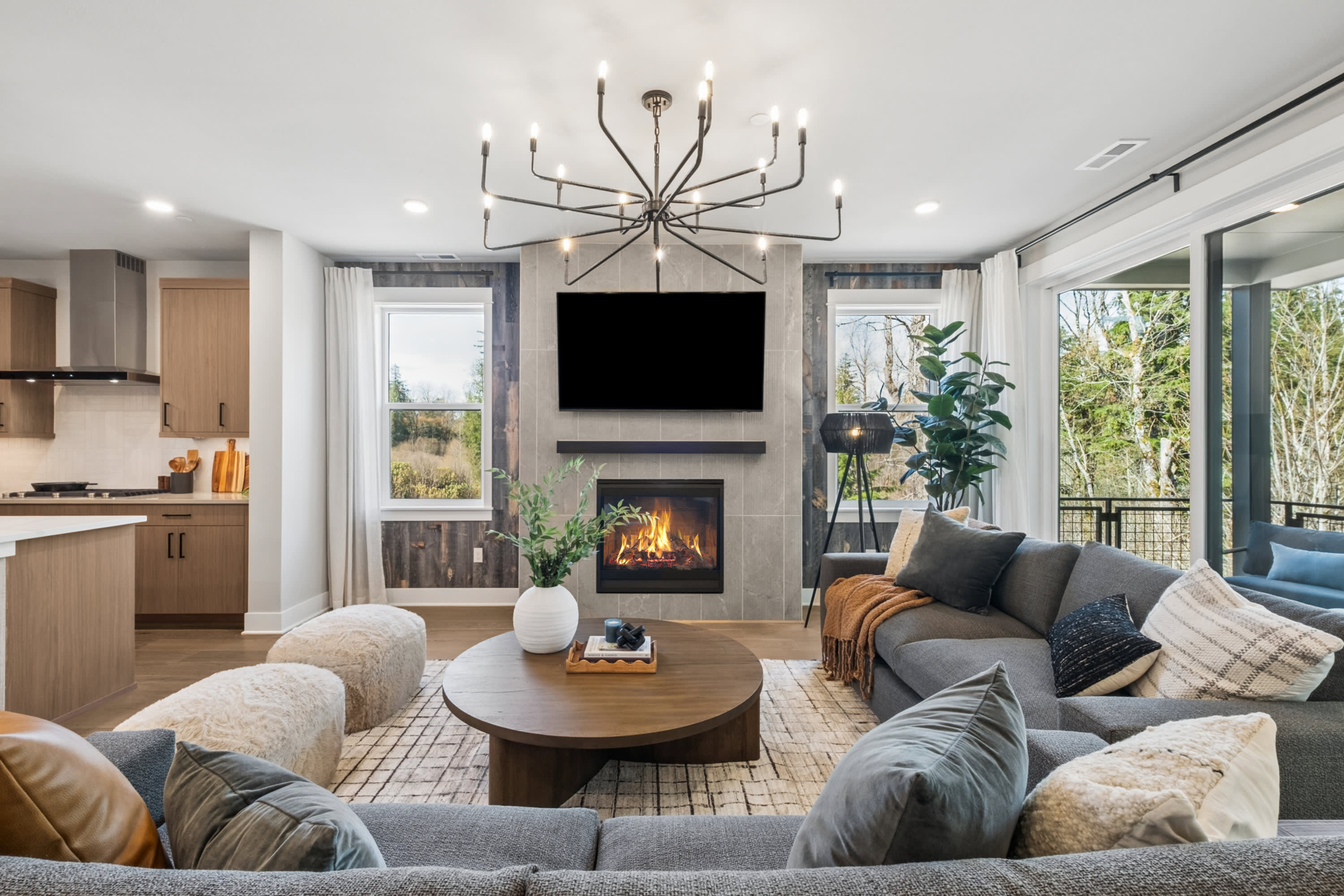 A cozy and inviting living room with a fireplace, a large chandelier, and a comfortable seating arrangement surrounding a wooden coffee table.