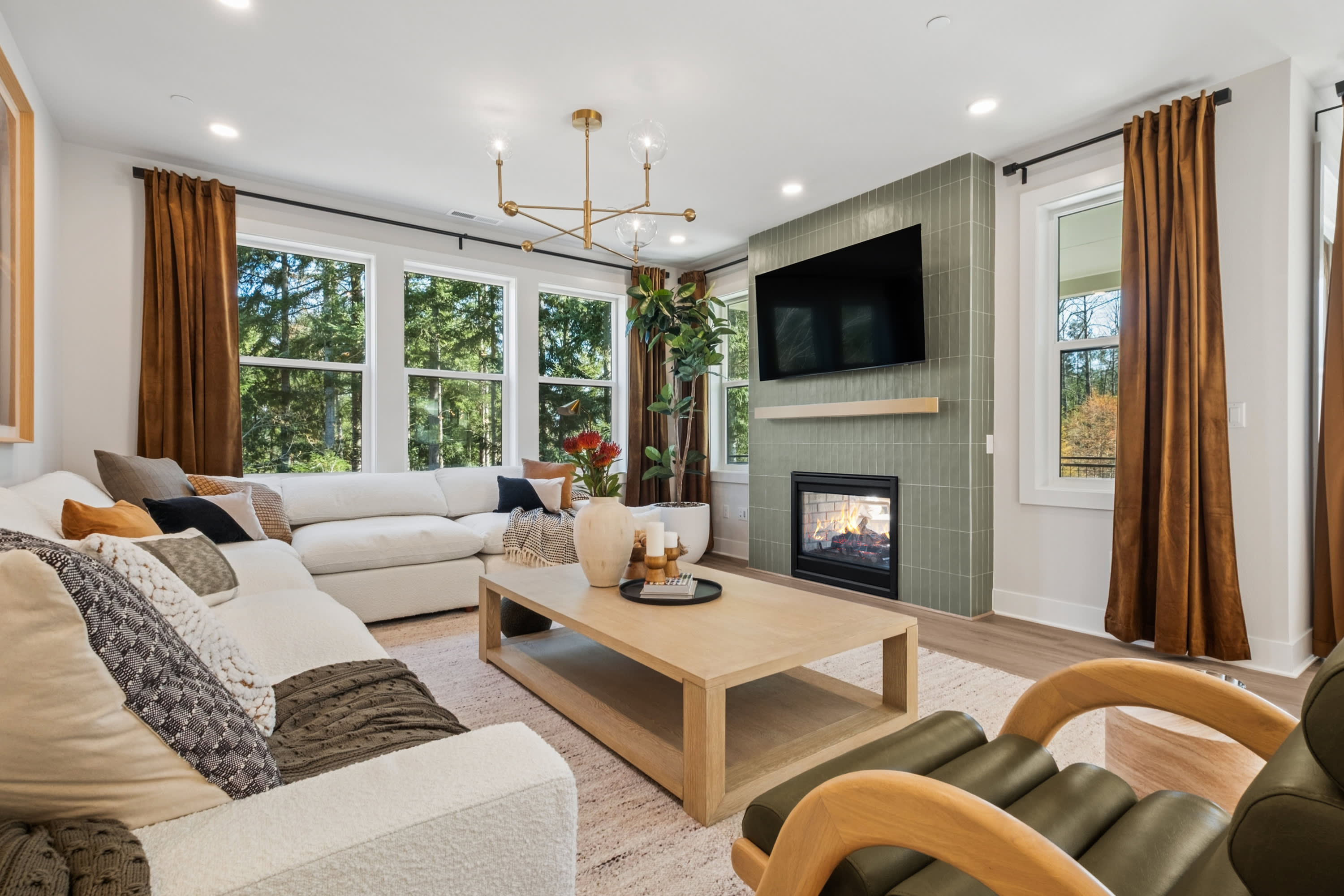 A cozy and inviting living room with a fireplace, large windows, and a mix of neutral and warm-toned furnishings, creating a comfortable and visually appealing space.