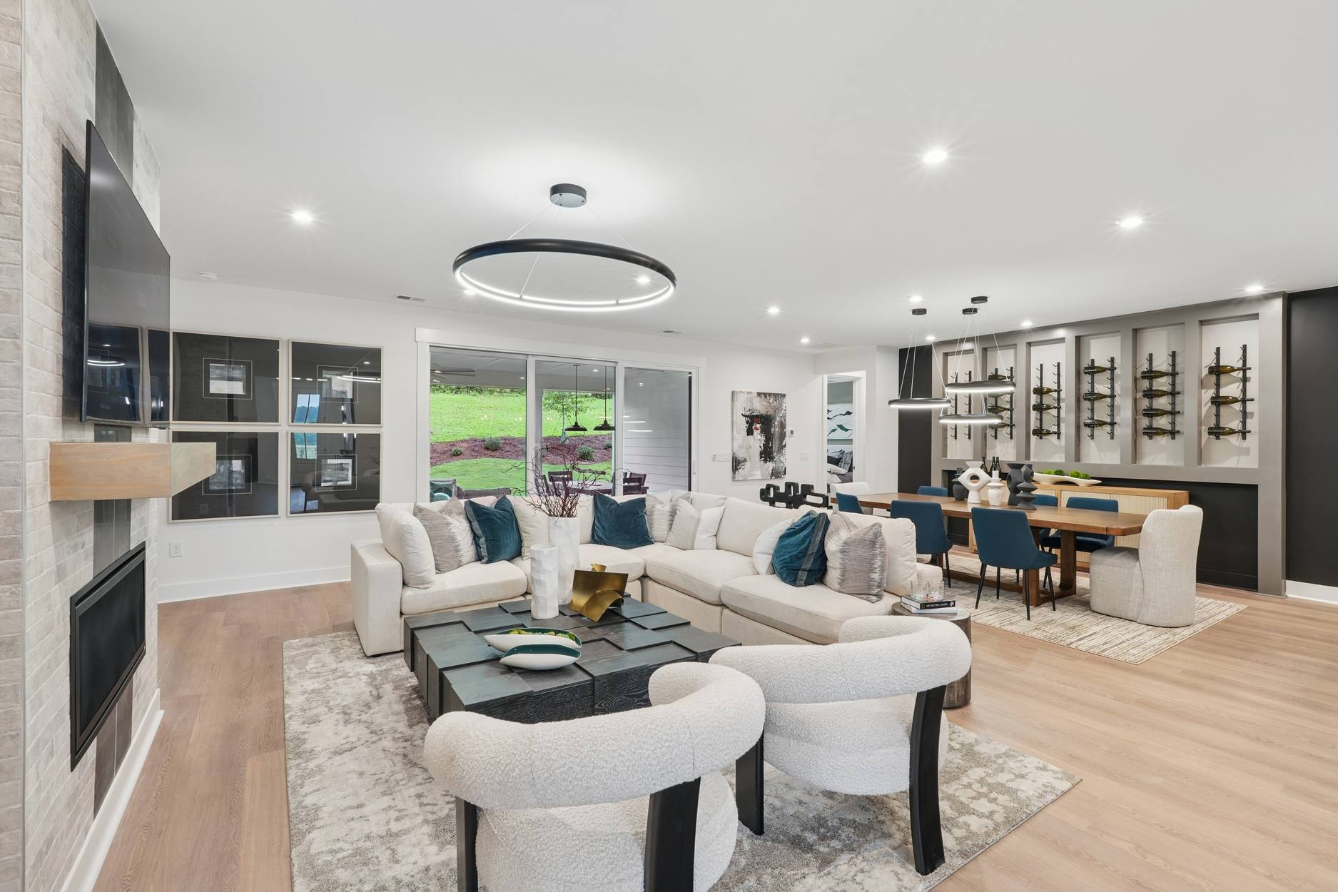 A modern and spacious living room with a large sectional sofa, a dining area, and a kitchen visible in the background, all featuring a sleek and minimalist design.