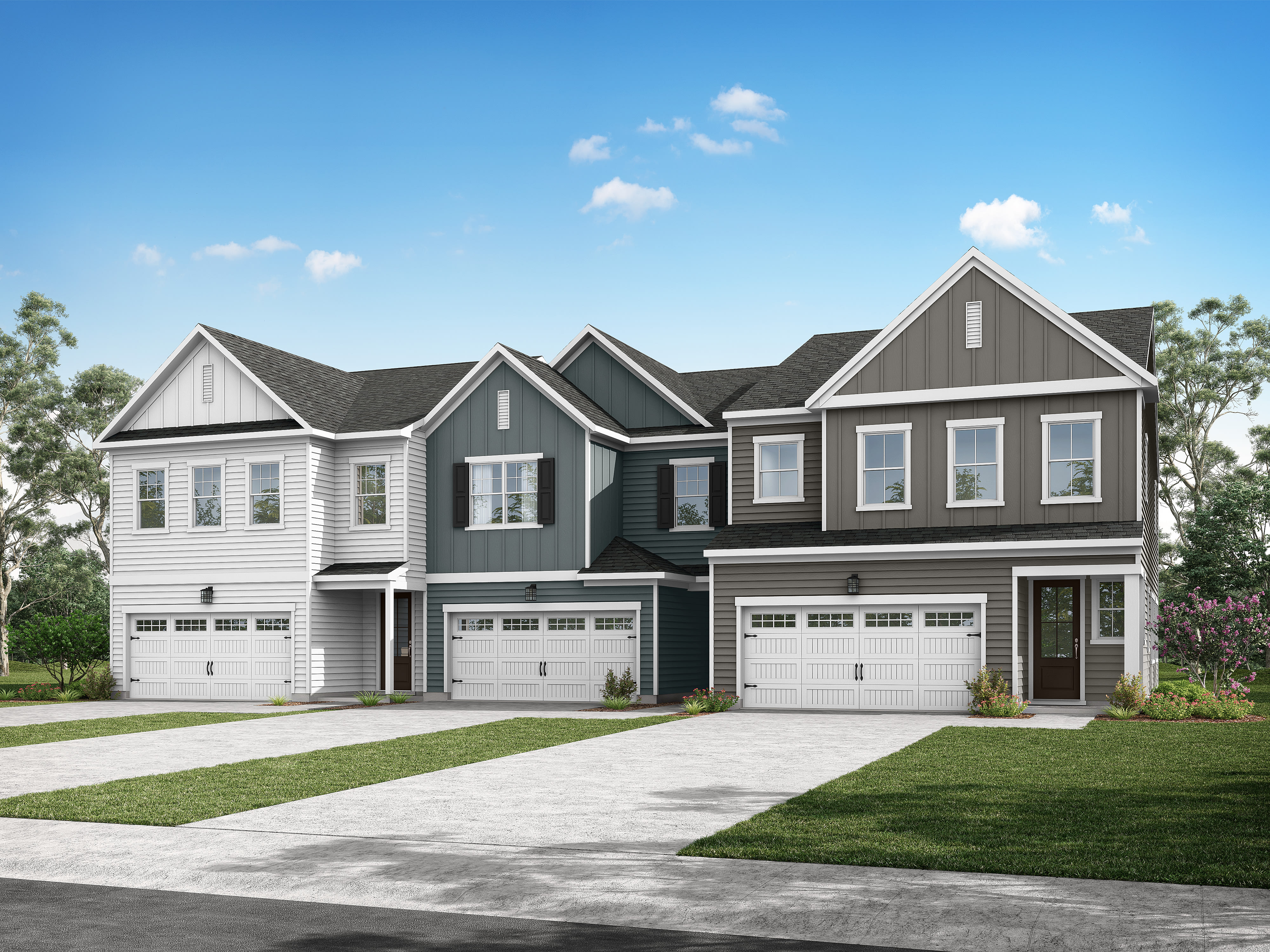 A row of modern, two-story townhouses with gray and white siding, gabled roofs, and attached garages sits on a grassy lawn against a backdrop of a clear blue sky with scattered clouds.