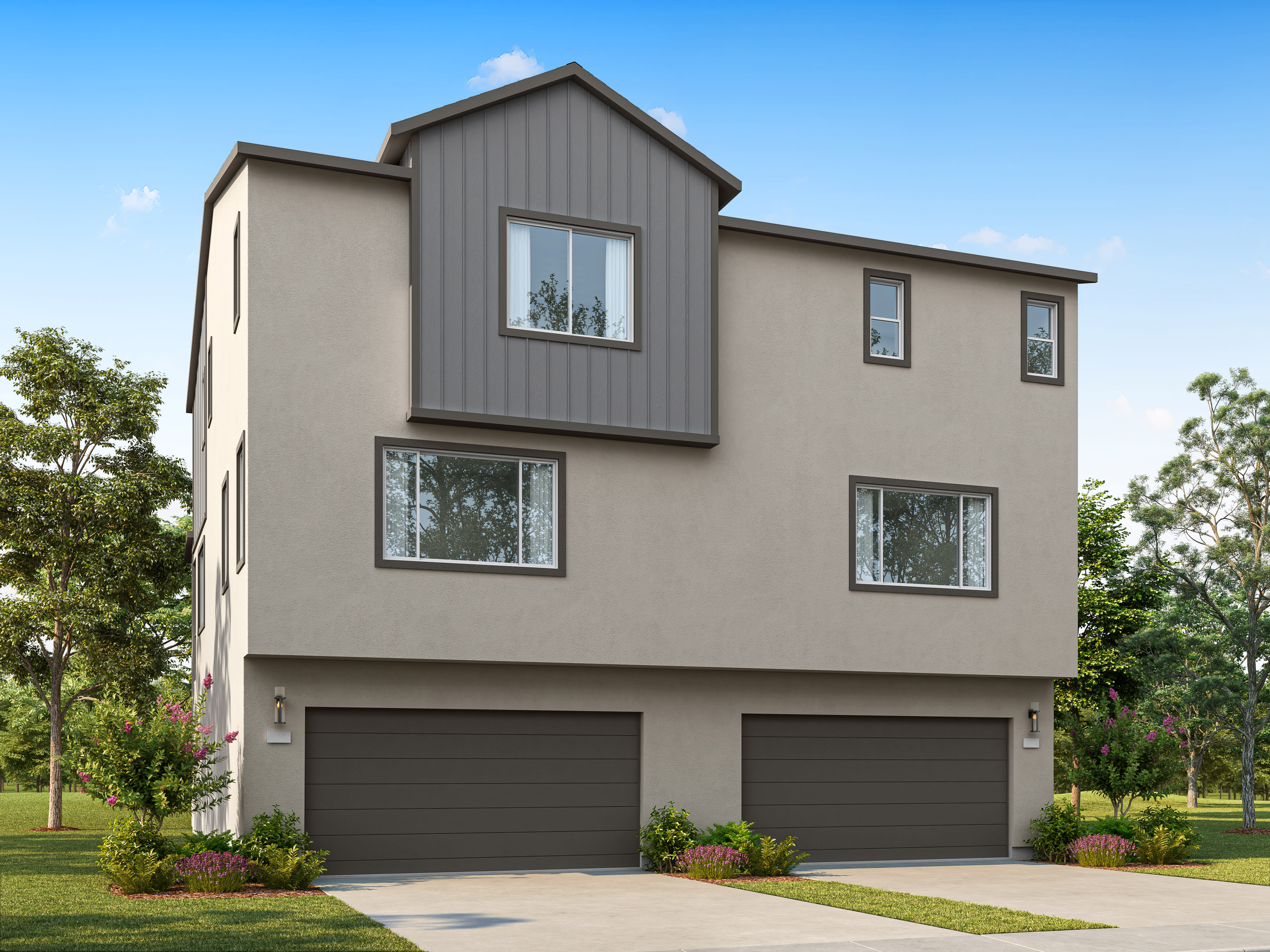 A modern, three-story townhouse with a gray metal roof accent and two garage doors sits in front of a bright blue sky with scattered trees.