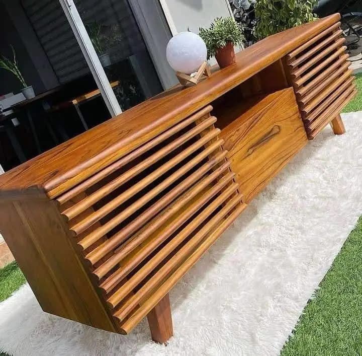 Solid wood TV stand with storage drawers holding media boxes in Kenya