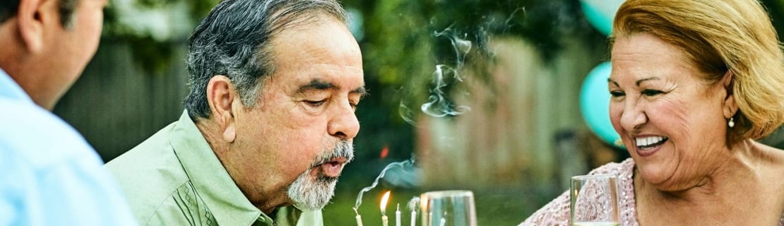 Senior Woman Looking At Man Blowing Birthday Candles