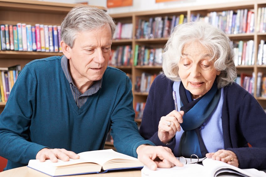 Senior couple reads in library 