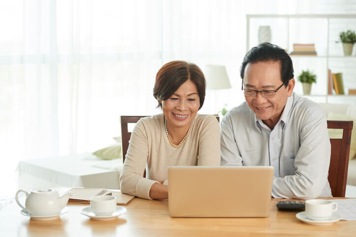 A couple uses a laptop computer on a table at home