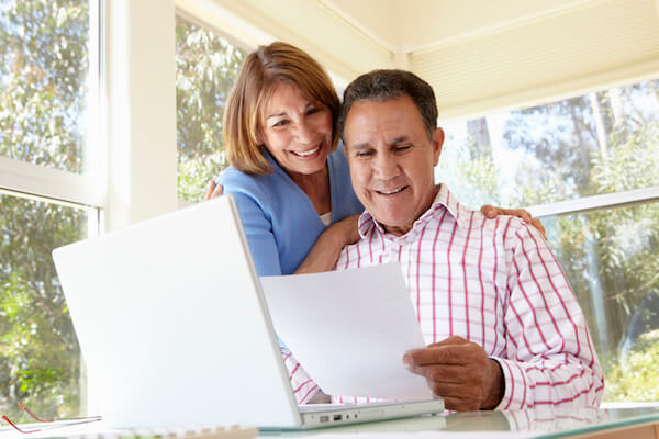 Smiling couple reviews Medicare information on their laptop computer