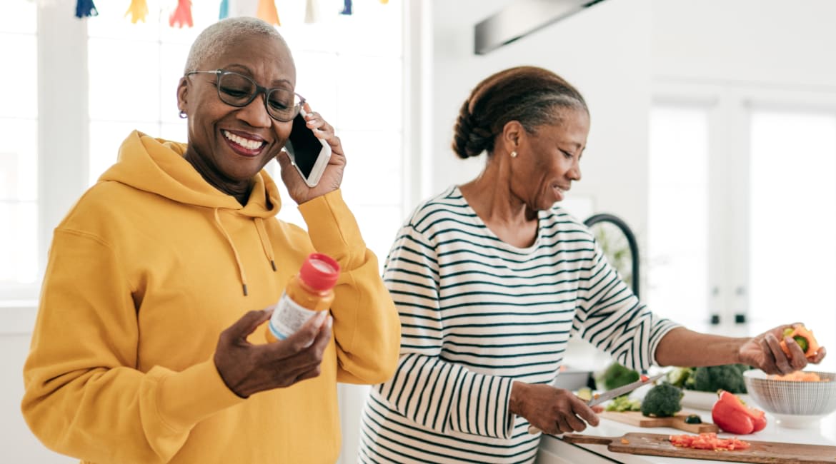 Woman cooking and another woman talking on the phone in the kitchen