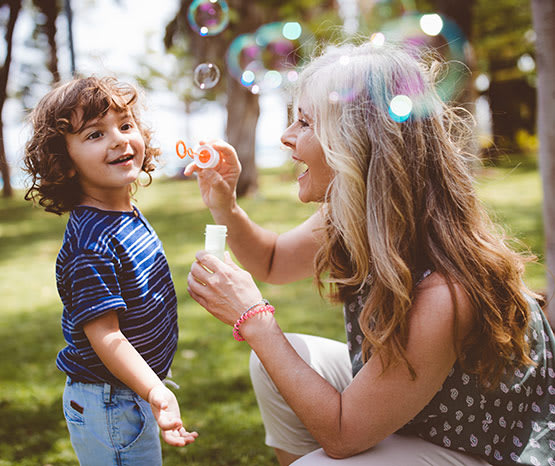 Woman and child blowing bubbles outside